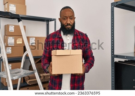 African american man working at small business ecommerce relaxed with serious expression on face. simple and natural looking at the camera. 