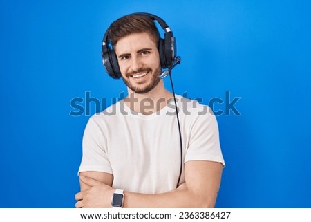 Hispanic man with beard listening to music wearing headphones happy face smiling with crossed arms looking at the camera. positive person. 