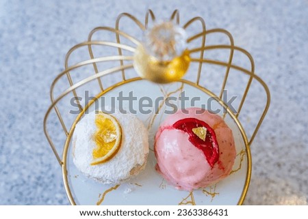 Filled donuts with orange and strawberry toppings and a gold leaf on top. Strawberry Cake Glazed Donuts. Doughnuts with jam filling in golden bird cage