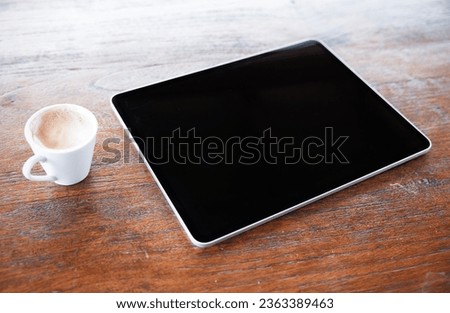 Tablet computer and cup of coffee on old wooden desk