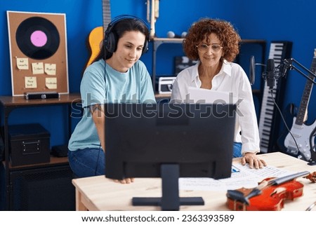 Two women musicians composing song using computer at music studio Royalty-Free Stock Photo #2363393589
