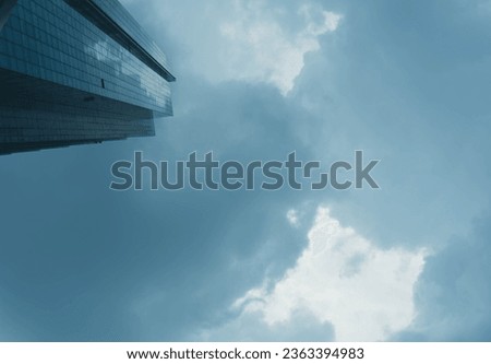 Modern skyscraper building with glass facade and cloudy sky