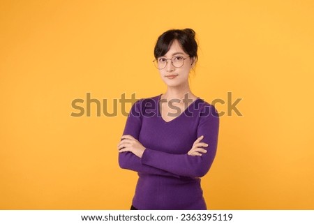 Lifestyle, people emotions and casual concept. Confident nice smiling young asian woman cross arms chest confident, listening to coworkers, taking part conversation isolated on yellow background.