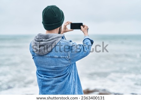 Young bald man make photo by smartphone at seaside