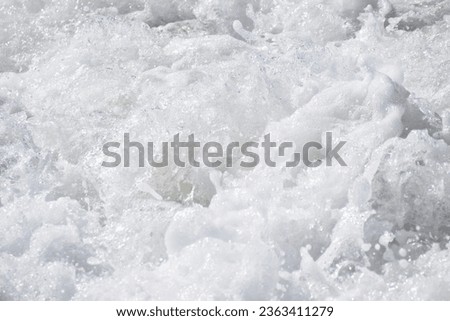 TURBULENT BRIGHT FOAMING WHITE WATER raging in powerful force of currents, crashing down a river, a breaking ocean wave or surging electric turbines Royalty-Free Stock Photo #2363411279