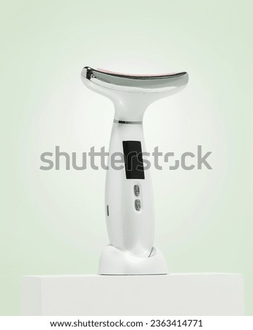 White Face and Neck Beauty Device Massager with Red Light Therapy on pastel green background 