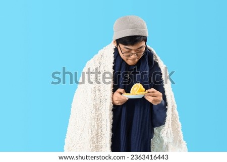 Ill Asian man with lemon on blue background