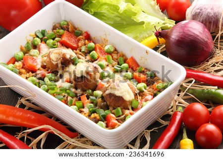Casserole with rice meatballs and vegetables on wooden background