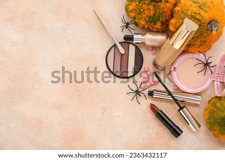 Composition with different makeup products and Halloween decor on beige background