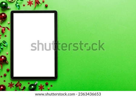 Christmas online shopping from home tablet pc with blank white display top view. Tablet with copy space on colored background with Christmas decorations balls,. Winter holidays sales background.