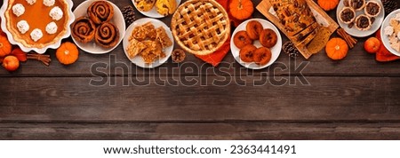 Autumn desserts top border. Table scene with various traditional fall sweet treats. Top view over a rustic wood banner background. Copy space. Royalty-Free Stock Photo #2363441491