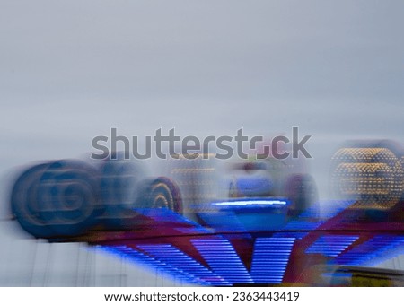 motion blur of ride at night  fair  lights moving bright lights on carnival ride at amusement park in evening slow shutter speed of multicolor circular spiral lights horizontal background backdrop 