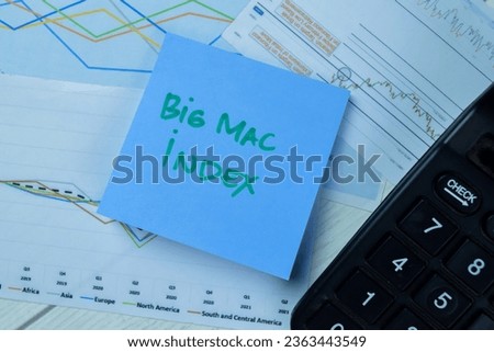 Concept of Big Mac Index write on sticky notes isolated on Wooden Table.
