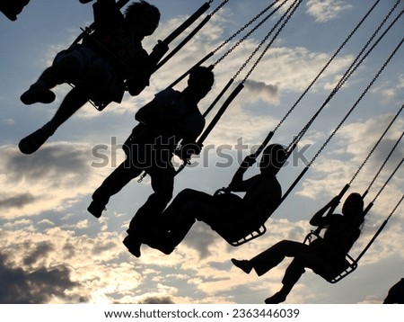 People ride on a carousel. Silhouettes of people riding on a carousel at sunset.