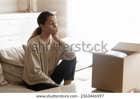 Upset annoyed young woman irritated by bad delivery service, unboxing parcel, looking at open cardboard box, dissatisfied customer received wrong or broken internet store order, complaint Royalty-Free Stock Photo #2363446597
