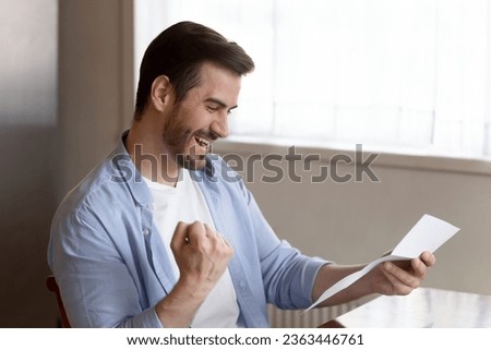 Overjoyed man reading good news, holding paper sheet, celebrate success, showing yes gesture with hand, get loan approval notification or new job, taxes refund, great college exam results Royalty-Free Stock Photo #2363446761