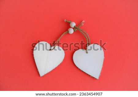 Two wooden pendant hearts on a red background. High quality photo