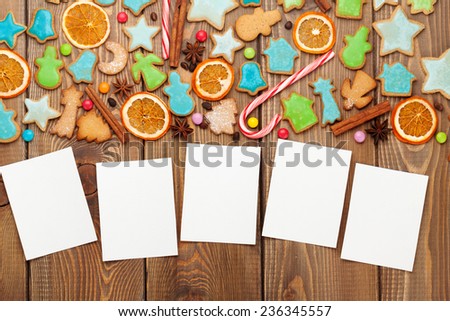 Christmas wooden background with photo frames, candies, spices and gingerbread cookies