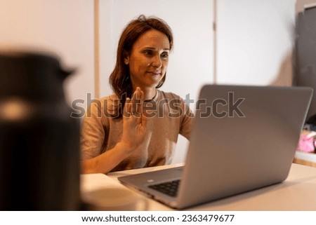 40 year old woman working at night connected to online meeting greeting for meeting with another time zone