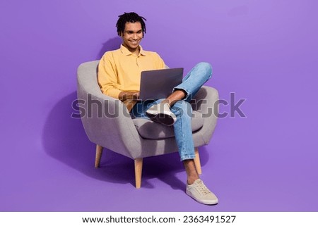 Full body length photo of young guy sit comfort armchair with netbook entertain watching videos laptop isolated on violet color background Royalty-Free Stock Photo #2363491527