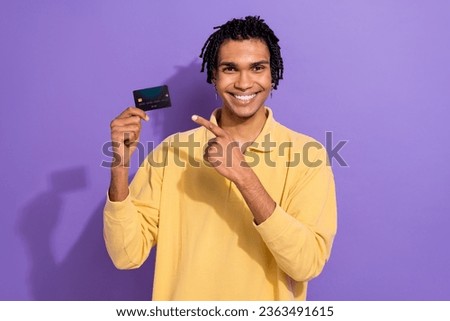 Photo of satisfied nice man wear yellow trendy clothes demonstrate money buy pay buy card nfc isolated on purple color background