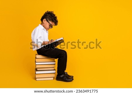 Full size profile photo of small clever schoolchild sit pile stack book read empty space isolated on yellow color background Royalty-Free Stock Photo #2363491775