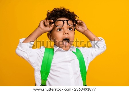 Photo of astonished little boy hands touch eyewear open mouth look empty space isolated on yellow color background