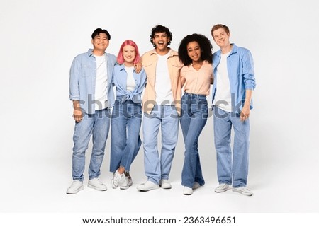 Happy young multiracial students posing, hugging, looking and smiling at camera, posing isolated on white studio background, copy space, full length. Study abroad, modern study and teamwork.