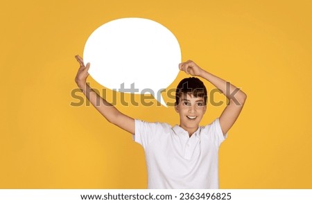 Surprised cheerful european teenage boy hold abstract cloud for thoughts at school, isolated on orange studio background. Idea for study, knowledge, ad and offer, people emotions