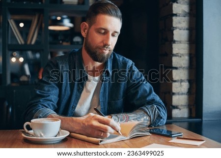 Man hand with pen writing on notebook on a wooden table. Royalty-Free Stock Photo #2363499025