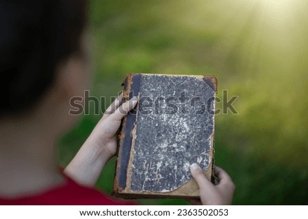 The child is holding an old book in his hands.Search for information in the vintage encyclopedia. Ancient historical reference books.