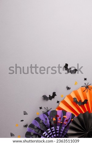 Get ready to the ghosts at Halloween bash. Top view vertical flat lay of paper fans, scary elements on grey background with commercial placeholder