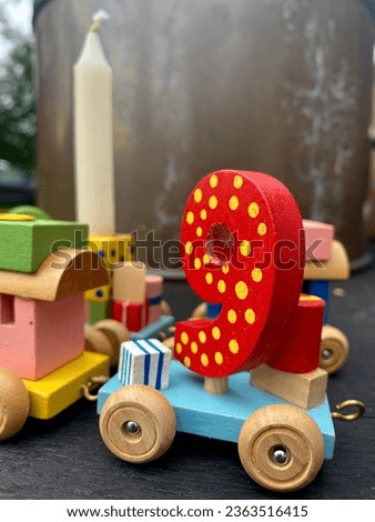 Colorful wood number and toy train, focus on number 9. with background of flowers on pot