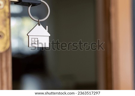 Keychain with a house on the background of an open door