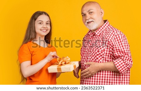 happy teen girl and grandfather with present box for anniversary