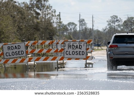 Hurricane flooded street with road closed signs blocking driving of cars. Safety of transportation during natural disaster concept