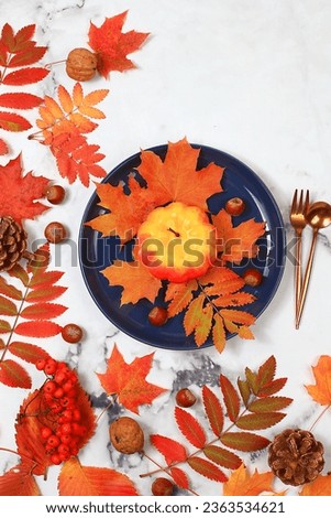 Autumn abstract composition with maple leaves, pumpkins and rowan berries, still life, blue plate for menu layout, Thanksgiving concept, seasonal background, banner or screensaver,