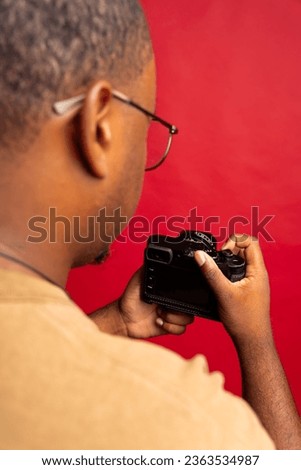 Black man photographer holding camera and changing camera settings with the camera adjustment buttons and dials