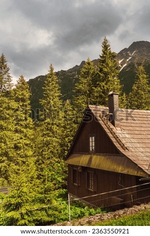 Wooden cabin in a mountainous forest with cloudy sky. A moody and peaceful image for themes of nature, environment, and lifestyle in Polish Tatras National Park, cloudy cloudy sky, summer day