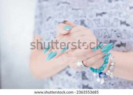 Woman's beautiful hand with long nails and baby blue manicure with bottles of nail polish