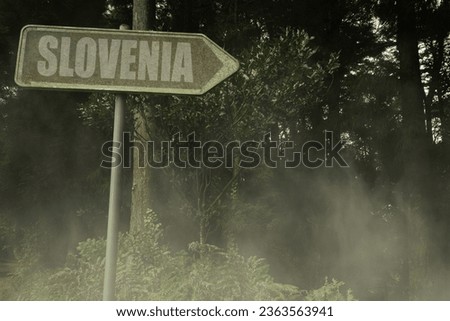 vintage old signboard with text slovenia near the green sinister forest