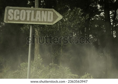 vintage old signboard with text scotland near the green sinister forest