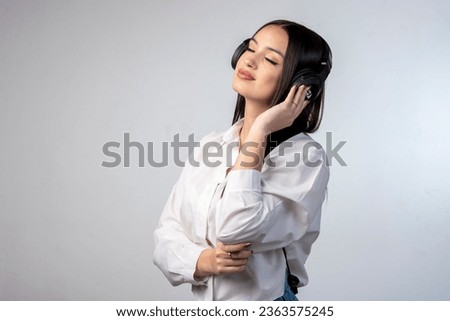 latin young woman with headphones very happy gesturing cheerful wearing white shirt and white background