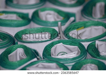 a bunch of banners rolled up in the printing industry. stacks of packed products in workspace. white tarpaulin printed in green.
