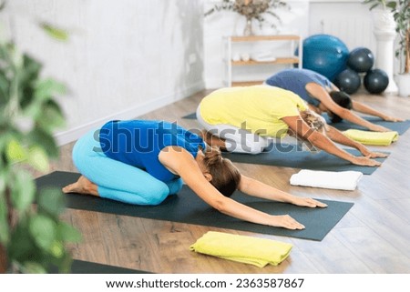 Grandmother, mother and teen son do sitting upside down tree pose, Adho Mukha Virasana in gym. Family three generations keep fit with exercise. Go in for sports. Healthy lifestyle Royalty-Free Stock Photo #2363587867