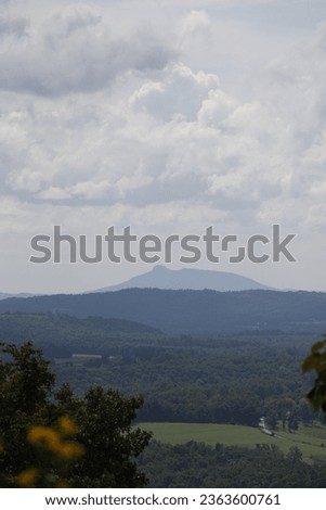 A beautiful view of pilot mountain in the distance and fluffy clouds hanging over top.