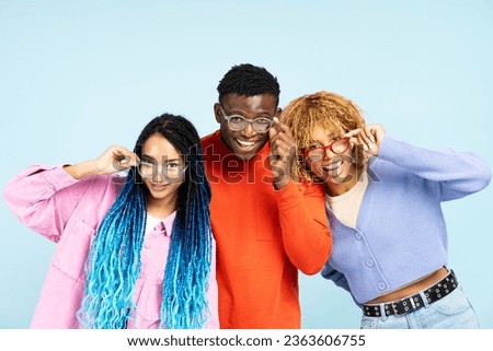 Group of smiling African American friends wearing colorful eyeglasses isolated on blue background. Happy fashion models with stylish hair looking at camera posing for pictures in studio Royalty-Free Stock Photo #2363606755