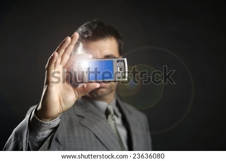 Businessman taking photos, mobile camera, black background [Photo Illustration]