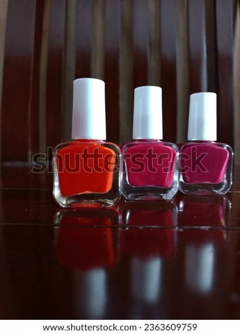 Three matte nail polishes of red, pink and purple color on wooden table background