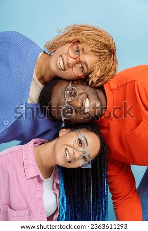 Group of smiling stylish African American friends wearing colorful glasses isolated on blue background. Happy fashion models with trendy hairstyle looking at camera posing for pictures in studio Royalty-Free Stock Photo #2363611293